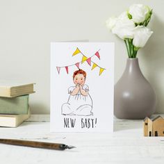 a card with a drawing of a baby on it next to some books and flowers