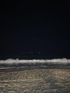 the beach is covered in waves at night