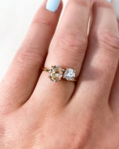 a woman's hand with a ring on it and two diamonds in the middle