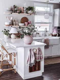 a kitchen with white cabinets and pink accessories on the counter top, along with wicker chairs