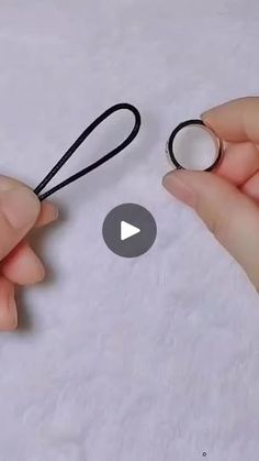 two hands holding scissors and string on top of paper