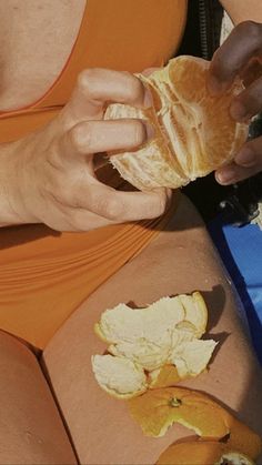 a woman in an orange bathing suit eating a sandwich