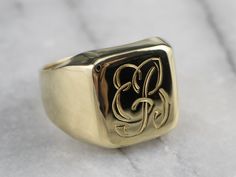 "Simple in design, this classic green gold signet ring is beautifully engraved with the letters \"EB\" on its front. Small in stature, this would make a wonderful gift for a young lady to wear, an heirloom that could transition to a pinky ring in later years. Metal: 14K Green Gold Top Measurements: 12 x 11 mm, Rectangle Monogram: \"EB\" in French Script Ring Size: 3.75 Marks: \"585\" Stamped on the inside band SKU #: K0HL5LTZ Each piece has been identified and graded by a Graduate Gemologist who Symbolic 14k Gold Initial Ring With Polished Finish, Symbolic Hallmarked Signet Ring For Formal Occasions, Symbolic Formal Signet Ring Hallmarked, Symbolic Formal Signet Ring With Polished Finish, Formal Symbolic Hallmarked Signet Ring, Collectible Yellow Gold Signet Ring With Initials, Symbolic Hallmarked Initial Ring For Formal Occasions, Symbolic Signet Ring With Engraving Option For Formal Events, Luxury Gold Engraved Ring With Hallmarks