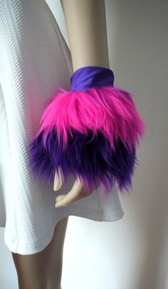 a mannequin's head with purple and pink fur on it, in front of a white wall