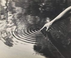 a person's hand reaching for something in the water that is rippled up