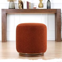 an orange ottoman sitting on top of a hard wood floor next to a wooden table