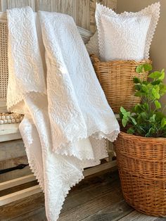 two white pillows and a basket on a wooden bench next to a plant in a wicker basket