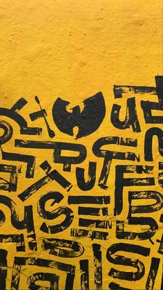 an image of graffiti written on the side of a yellow wall with black letters and numbers