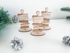 three wooden signs sitting on top of a table next to pine cones and fir trees