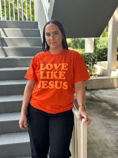 This comfortable, cotton shirt features the inspiring message "Love like Jesus". The phrase is printed in a bold yet graceful font, making it a perfect statement piece. The shirt color on color combines both style and a meaningful message, reminding you and those around you to embody the compassionate and selfless love that Jesus exemplified. Ideal for casual wear, community gatherings, or church events, this shirt serves as a daily reminder to lead with kindness and love. - Unisex Tee  - Puff Logo - 100% Cotton - 5.3 oz - Heavy Cotton - Recommended washing on cold and hang-drying. DESIGN ON SHIRT The design is located exactly as shown in the main picture. SIZING - Refer To the pictures for the size chart. CARE INSTRUCTIONS: - We recommend lightly hand-washing. If you want to use the washe Relaxed Fit Short Sleeve Shirt With Lettering, Inspirational Cotton Tops With Funny Text, Inspirational Short Sleeve Tops With Funny Text, Inspirational Short Sleeve Shirt With Graphic Print, Inspirational Graphic Print Short Sleeve Shirt, Inspirational Short Sleeve Graphic Print Shirt, Inspirational Cotton Shirt With Text Print, Inspirational Short Sleeve Shirt With Letter Print, Orange Cotton Shirt With Letter Print