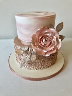 a pink and gold wedding cake with flowers on top