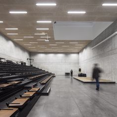 an empty auditorium with rows of seats and people in the distance walking through it,