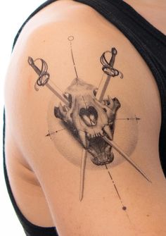 a woman's shoulder with a skull and two swords on it