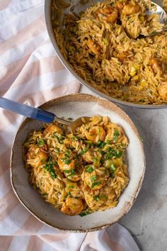 two bowls filled with shrimp and rice on top of a white table cloth next to a spoon