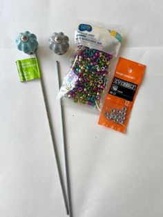 some beads are laying next to each other on a white tablecloth with scissors and plastic bags