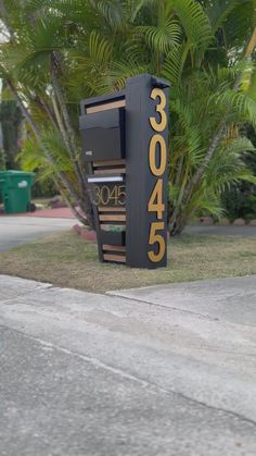 a mailbox sitting on the side of a road next to palm trees and bushes