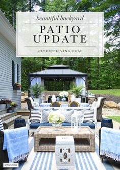 an outdoor patio with blue and white striped rugs, wicker furniture, and a gazebo in the background