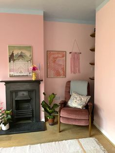 a living room with pink walls and a chair in front of a fire place next to a fireplace