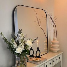 a vase filled with flowers sitting on top of a white table next to a mirror