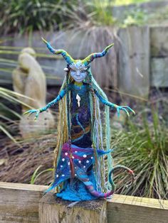 a statue of a woman with long hair and horns on top of a wooden fence