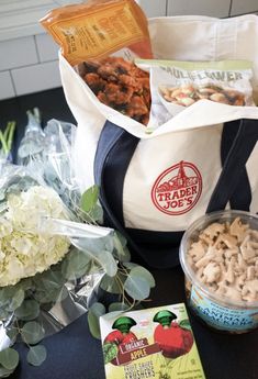 a bag full of food sitting on top of a table next to flowers and other items