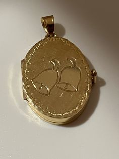 This hand-made oval locket is as sentimental and unique as it gets. It is a perfect baby shower or a Communion present. It is made of 14 karat gold. It is both beautiful and functional. Most lockets can hold 2 pictures but this one can hold 4 special photos close to your, or your loved one's heart! The photos are easy to slip through slots at top of locket. It is hard to match the workmanship of this locket and it's engraving. It was crafted by a very talented jeweler in the NYC jewelry district between 1970 - 1980. Lockets are his legacy and his remaining inventory is being sold on this site. Most are one of a kind and will not be available after it is sold. The best jewelers are in awe of the workmanship and you will always get compliments. This precious locket and can easily become a he Classic Oval Locket Necklace Stamped 14k, 14k Yellow Gold Locket Necklace For Anniversary, Gold Oval Locket Necklace As A Gift, Heirloom Yellow Gold Locket Necklace With Charms, Gold Oval Locket Necklace For Anniversary, Formal Gold Oval Locket Necklace, Gold Oval Locket Necklace For Keepsake, Gold Oval Link Locket Necklace For Anniversary, Heirloom Yellow Gold Locket Necklace For Anniversary