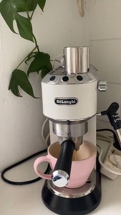 a coffee maker sitting on top of a counter next to a potted plant