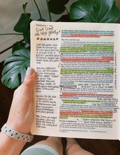 a person holding up an open bible in their left hand with writing on the pages