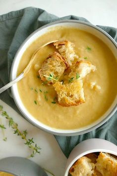 there is a bowl of soup with bread in it and a spoon next to it