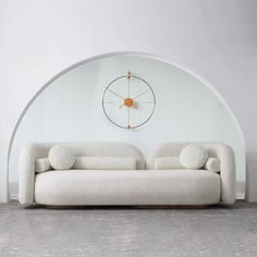 a white couch sitting in front of a wall mounted clock on the side of a wall