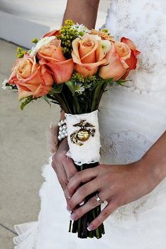 a bride holding a bouquet of roses in her hand and wedding ring on her finger