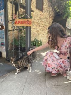 a woman petting a cat on the sidewalk