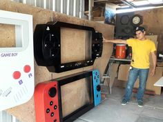 a man standing next to two nintendo wii game controllers in a room with other video games on the wall