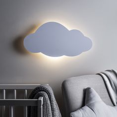 a cloud shaped light on the wall above a crib