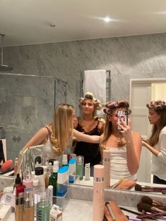 three women standing in front of a bathroom mirror