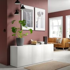 a living room filled with furniture and a potted plant on top of a white cabinet