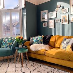 a living room filled with yellow couches and chairs next to a wall covered in pictures