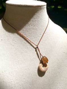 a necklace on a mannequin with a wooden bead hanging from it's end