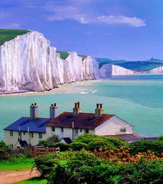 a house on the shore with white cliffs in the background