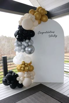 the balloon arch is decorated with black, white and gold balloons