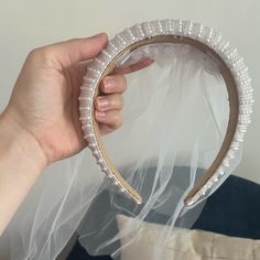 a person holding up a white headband with pearls on the top and bottom of it