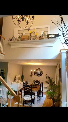 a dining room table and chairs under a chandelier in a house with stairs leading up to the second floor