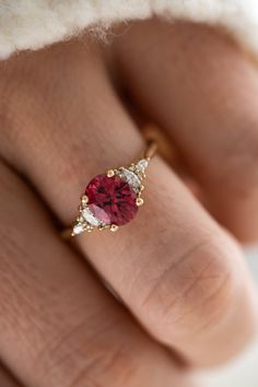 a woman's hand with a ring on it and a red stone in the middle