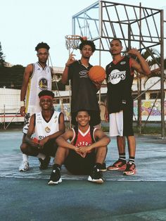 a group of young men standing next to each other holding basketballs on top of a basketball court