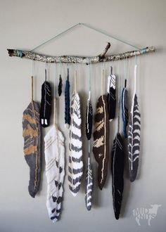 a group of feathers hanging on a wall next to a string with arrows attached to it