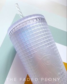 a plastic cup with a straw in it sitting on top of a colorful tablecloth