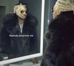 a man with dreadlocks is looking at himself in the mirror while wearing a fur coat