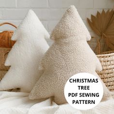 two christmas tree pillows sitting on top of a bed next to a wicker basket