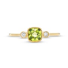 a yellow gold ring with an oval cut green stone and two diamonds on the band