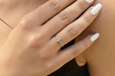 a woman's hand with a diamond ring on her left wrist and white nails